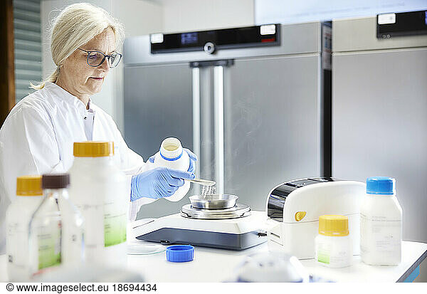 Scientist measuring chemical on weight scale in laboratory