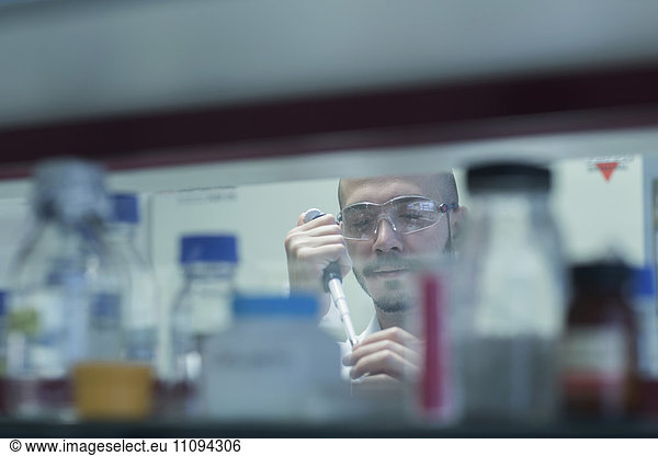 Scientist pipetting sample in test tube in research laboratory