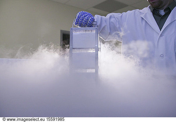 Scientist removing tissue samples from a storage tank of liquid nitrogen