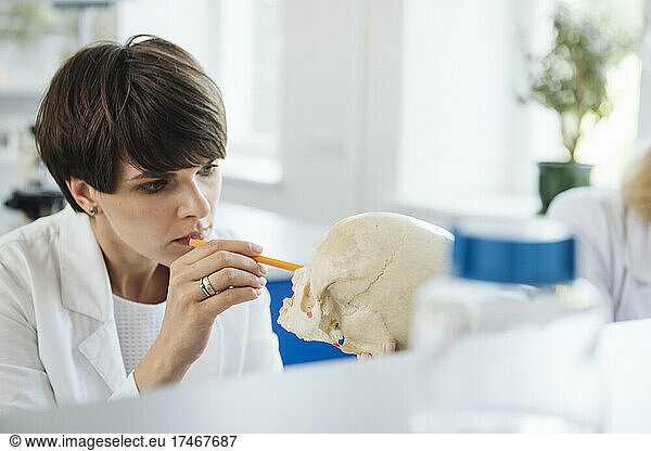 Scientist researching over human skull at workplace