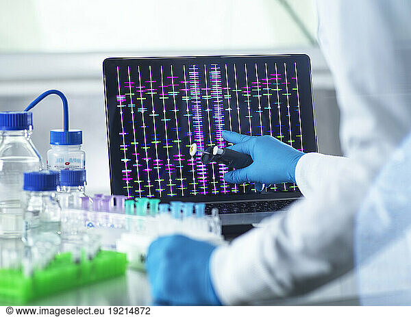 Scientist reviewing DNA information on laptop in laboratory