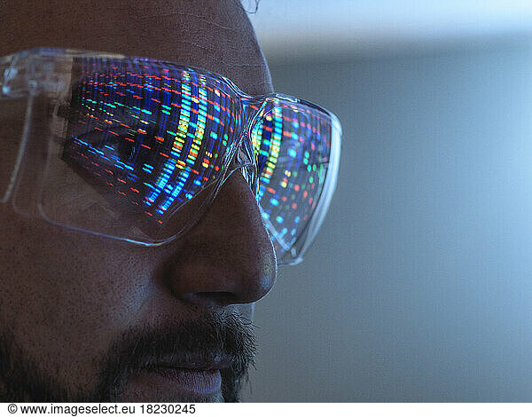 Scientist wearing protective eyeglasses analyzing DNA data in laboratory