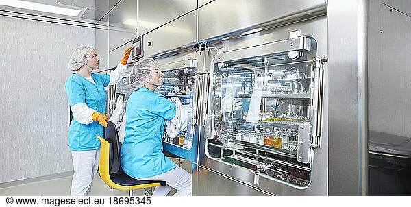Scientists examining chemicals in microbiological safety cabinet