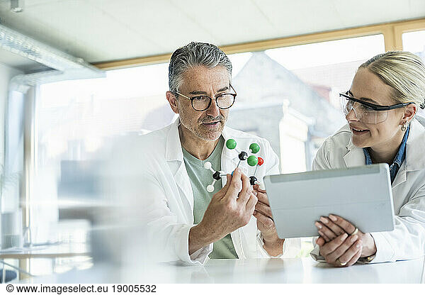 Scientists researching on molecular structure with tablet PC in laboratory