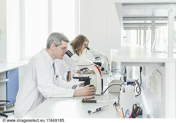 Scientists researching through microscope in laboratory