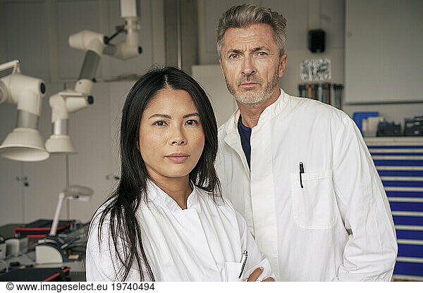 Scientists standing with mature colleague in laboratory