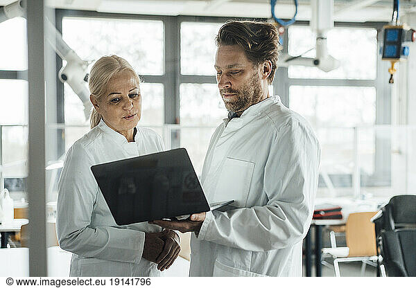 Scientists together discussing over laptop