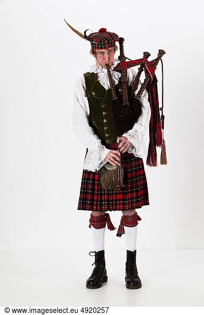 scotsman dressed in plaid pleated skirt playing the bagpipe