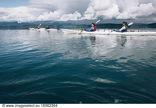 Sea kayakers paddling pristine waters of an inlet on the Alaska coastline.