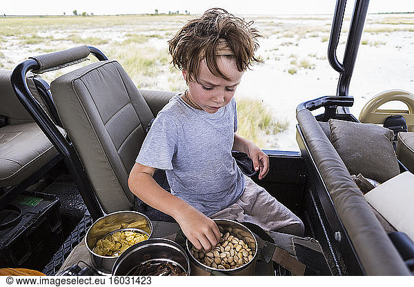 Sechsjähriger Junge isst Snacks im Safari-Fahrzeug  Botswana
