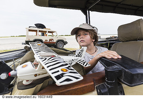 Sechsjähriger Junge mit Spielzeug im Safari-Fahrzeug  Botswana