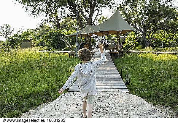 Sechsjähriger Junge spielt mit Spielzeugflugzeug  Zeltlager  Botswana