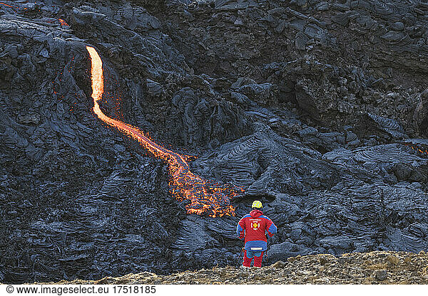 security man observe incandescent flowing volcanic lava in volcano