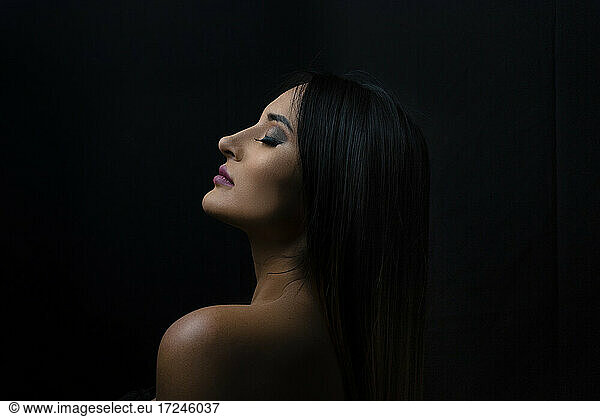 Seductive woman with eyes closed against black background