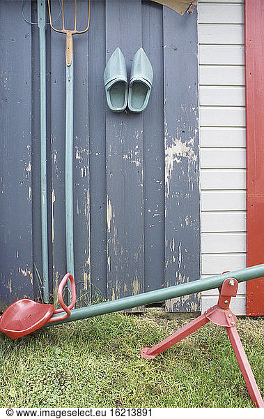 Seesaw in front of wooden wall with gardening tools