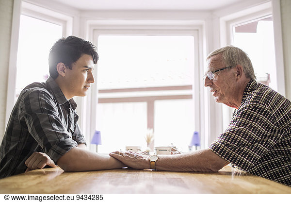 Seitenansicht des tröstenden Enkels des Großvaters bei Tisch