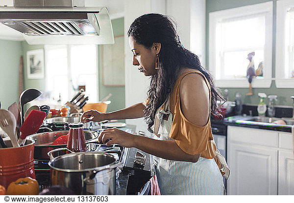 Seitenansicht einer Frau  die in der Küche Essen zubereitet