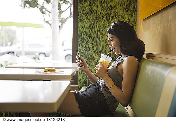 Seitenansicht einer Frau  die während eines Drinks im Restaurant telefoniert