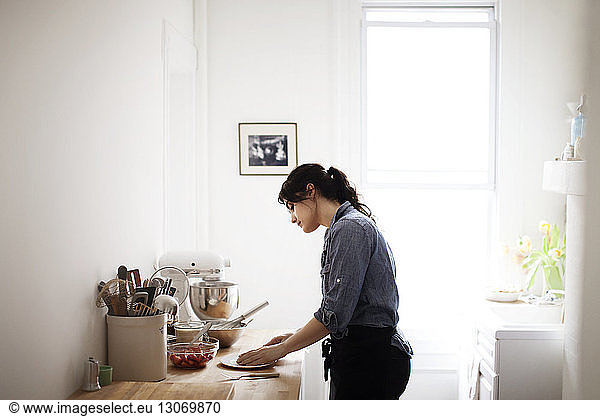 Seitenansicht einer Frau  die zu Hause Essen zubereitet