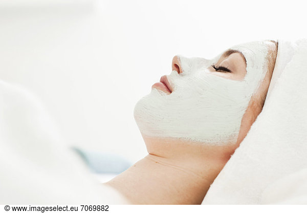 Seitenansicht einer jungen Frau beim Entspannen mit Gesichtsmaske im Beauty Spa