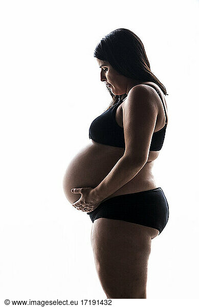 Seitenansicht einer schwangeren Frau auf weißem Hintergrund im Studio