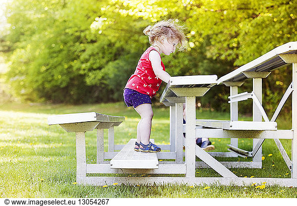 Seitenansicht eines auf einer Parkbank stehenden Mädchens