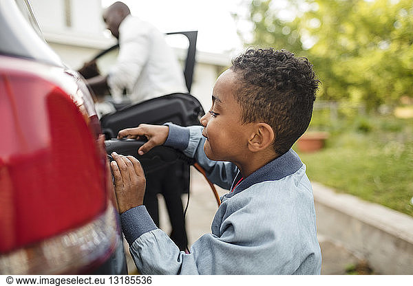 Seitenansicht eines Jungen beim Aufladen eines Elektroautos