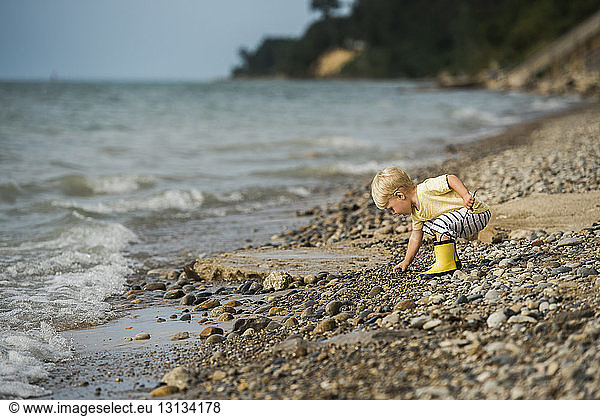 Seitenansicht eines Jungen beim Kieselsteinpflücken beim Spielen am Ufer