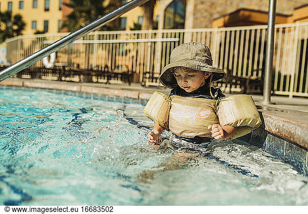 Seitenansicht eines Jungen im Wasser sitzend im Pool im Urlaub