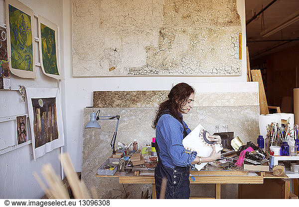 Seitenansicht eines Künstlers  der im Workshop Kunstwerke an einem Tisch hält