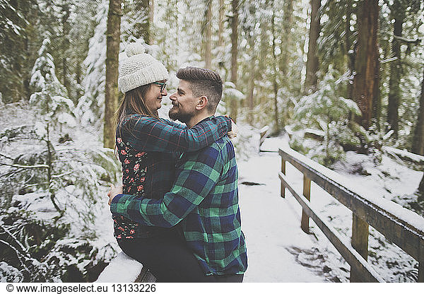 Seitenansicht eines liebenden Paares  das sich im Wald im Lynn Canyon Park im Winter Auge in Auge gegenübersteht