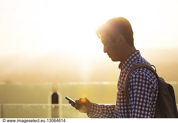Seitenansicht eines Mannes bei der Benutzung eines Mobiltelefons
