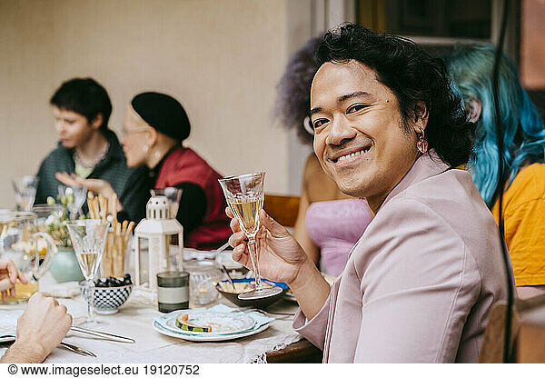 Seitenansicht Porträt von lächelnden Homosexuell Mann hält Getränk Glas während der Party im Hinterhof