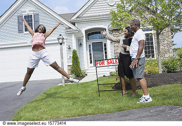 Seitenprofil eines Mannes mittleren Alters und eines Immobilienmaklers mit Blick auf eine springende Frau mittleren Alters