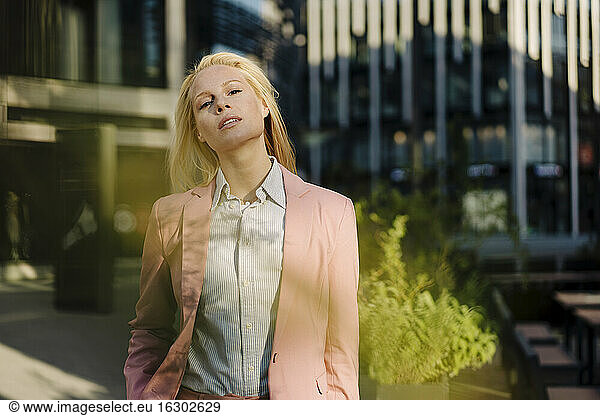 Selbstbewusste schöne blonde Geschäftsfrau in rosa Businesskleidung im Finanzviertel