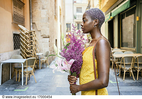 Selbstbewusster weiblicher Hipster mit Blumenstrauß in der Stadt