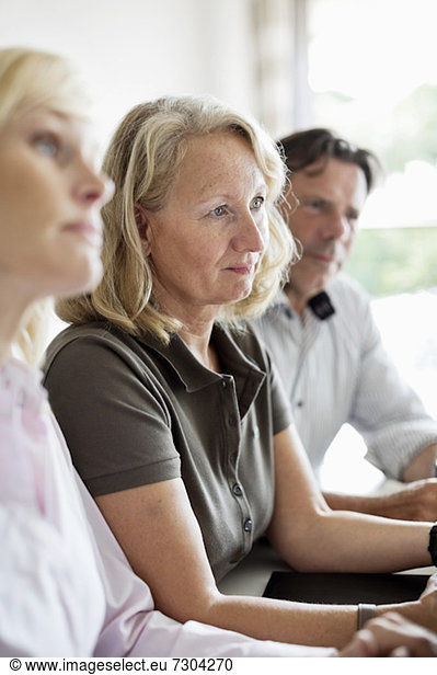 Selective focus of senior woman with colleagues sitting at business meeting