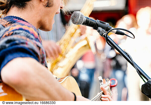 Selective focus on a face of a man singing and playing a guitar in the street