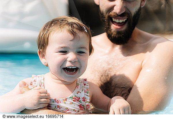 Selective focus on the face of a girl that is laughing in the water embracing a man