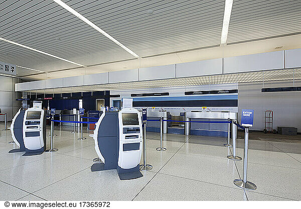 Self check-in desks and traditional baggage check in desks in an empty airport.