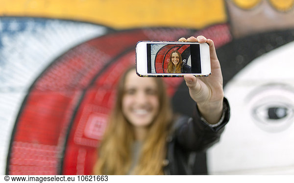 Selfie of smiling teenage girl on display of smartphone