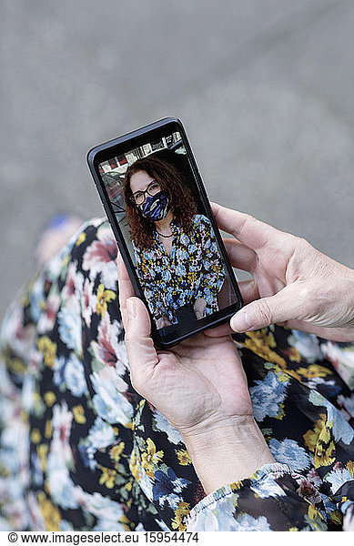 Selfie of woman with mask on smartphone