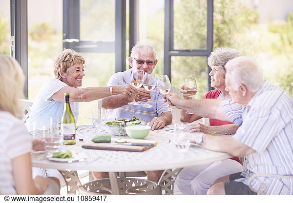 Senior adults toasting wine glasses at patio lunch