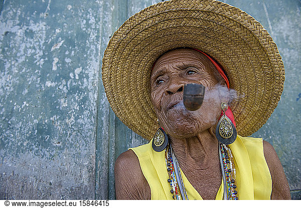 Senior Afro-Brazilian woman smoking pipe wearing straw hat