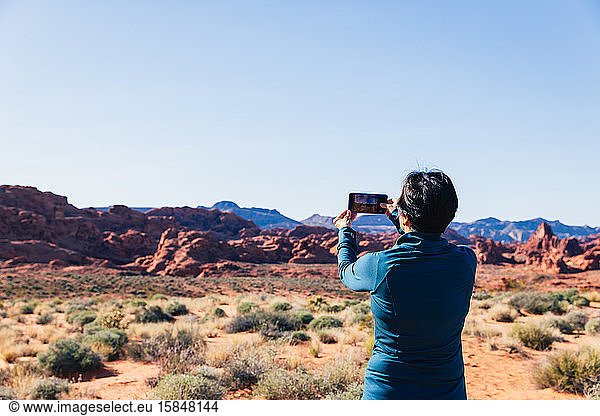 Senior Asian woman taking a photo of a desert landscape with her camer