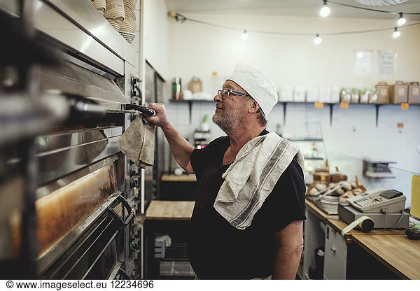 Senior baker standing by oven at bakery