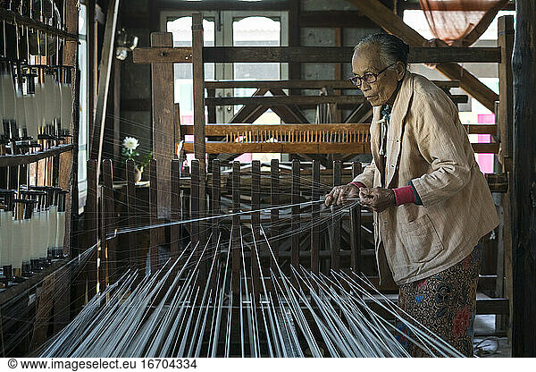 Senior Burmese woman preparing threads to work on loom  Lake Inle  Myanmar