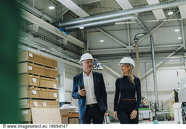 Senior businessman discussing with smiling colleague in carpentry factory