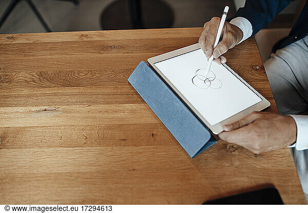 Senior businessman drawing on digital tablet in office