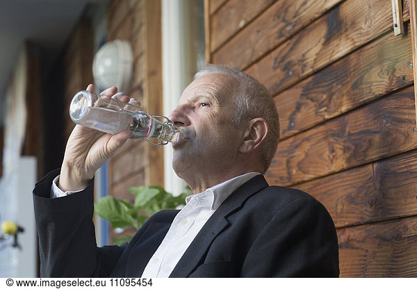 Senior businessman drinking water from a bottle  Freiburg im Breisgau  Baden-Württemberg  Germany
